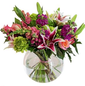 red and white lilies with greens in a vase