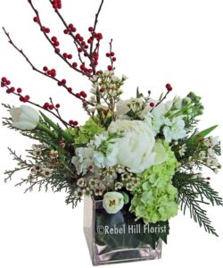 Enchanting arrangement of white flowers with red ilex and fragrant winter greens.