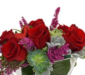 Love Boat is a lovely, quaint cluster of roses, succulents, accent flower and greens in a clear glass boat shaped vase