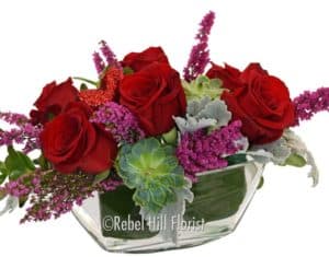 Love Boat is a lovely, quaint cluster of roses, succulents, heather and greens in a clear glass boat shaped vase